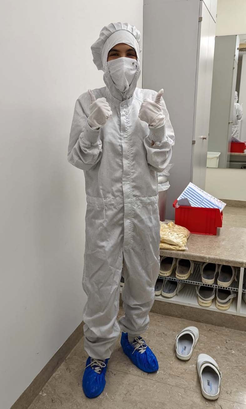 Undergraduate Research Opportunities participant Irene Pellini in a clean room dress shows thumbs up