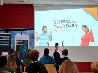 The third day was workshop day - the coaching of Dr. Amani Said empowered and motivated all of us A seminar room with attendees focused on a presentation slide encouraging the celebration of daily wins. The room features banners for Max Planck School  Matter to Life and DWI, Leibniz Institute for Interactive Materials.