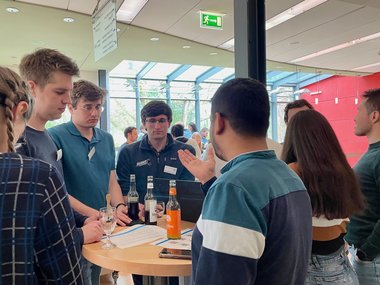 MtL students stand at a table and discuss