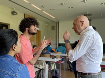 Prof. Stefan Hell is pictured in a conversation with two students