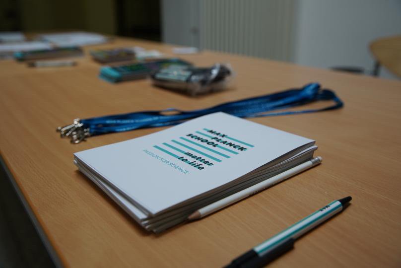 Close-up shot of a table with merchandise: Notebooks, keychains, pencils, etc. branded with the design of both schools