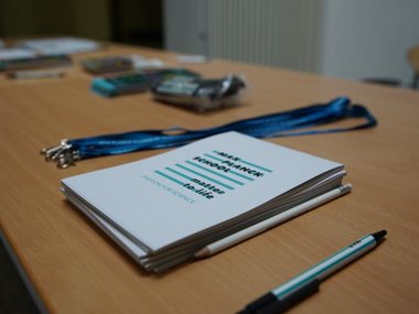 Close-up shot of a table with merchandise: Notebooks, keychains, pencils, etc. branded with the design of both schools