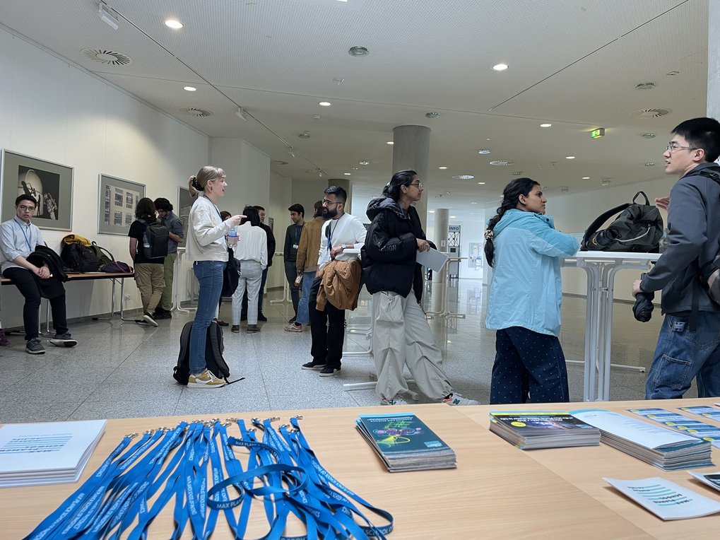 Students are talking and waiting in the foyer. A table with merchandise is seen in the foreground