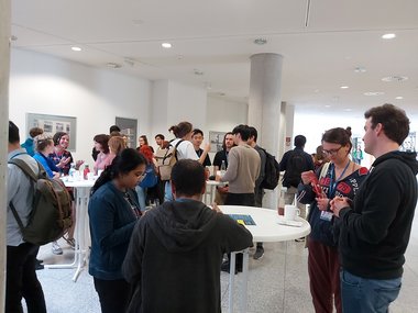 Students stand at round tables and converse