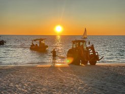 Sunset on the sea in Australia with boat in the water and tractor on the beach