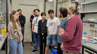 Students get an insight into Job Boekhoven’s lab A group of students stand in a lab during a tour by doctoral student Michele Stasi.