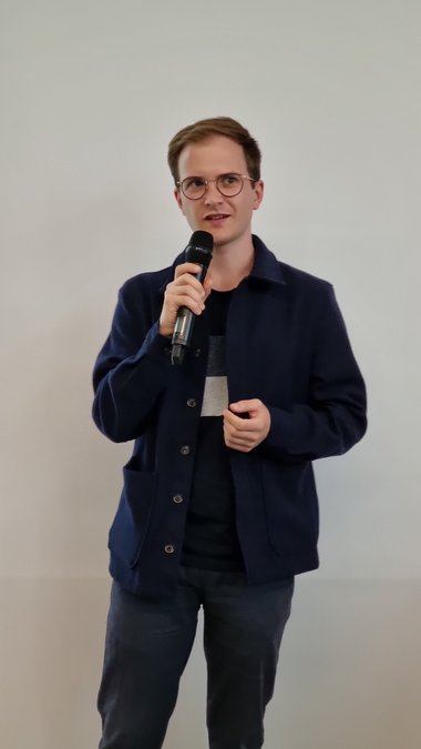 Arsenii Hordeichyk smiles slightly and speaks into the microphone he holds in his right hand.