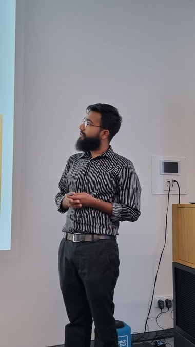 Mubarrat Mahin Mursalin looks to his left at his slides and gives his presentation.