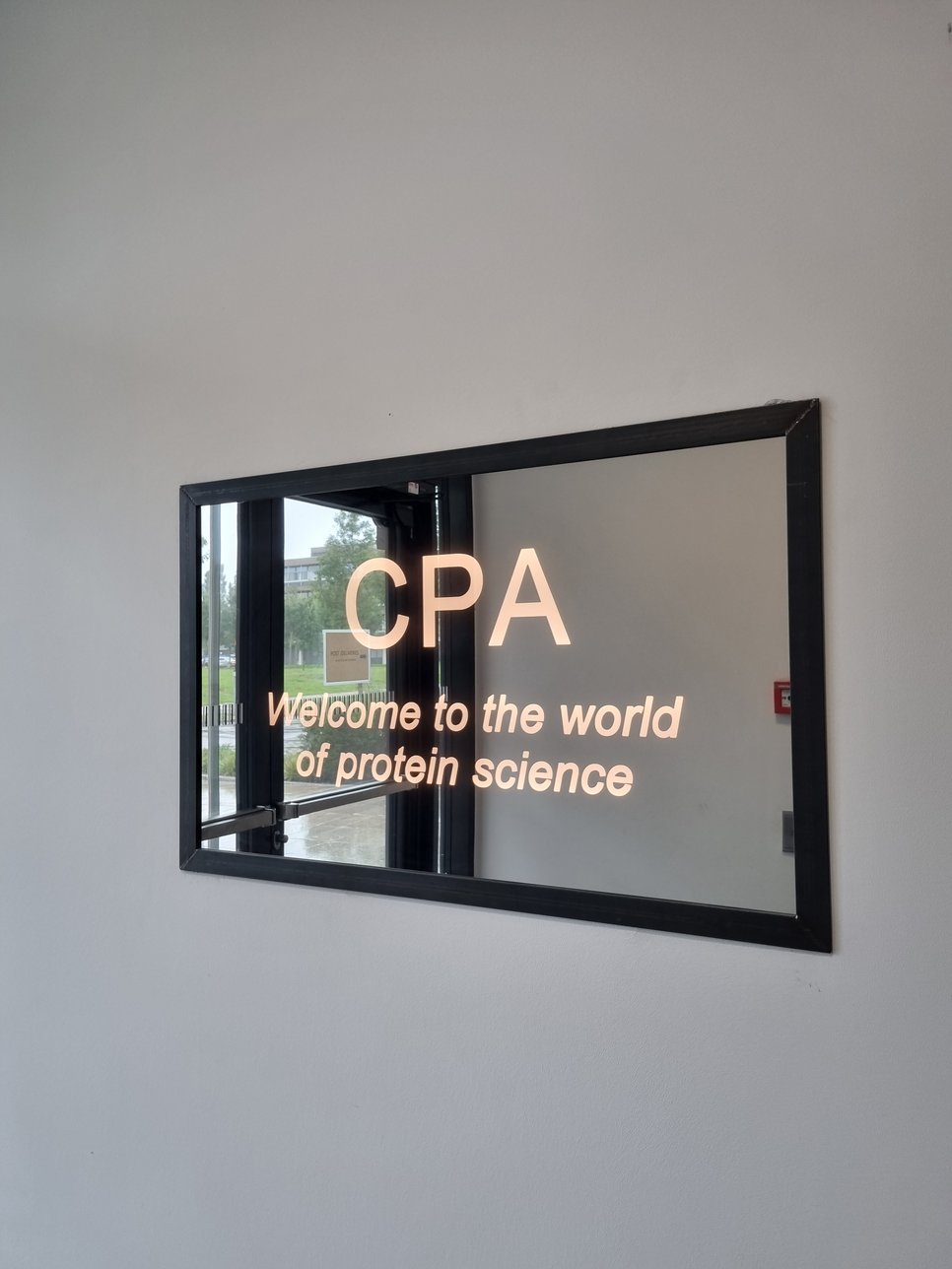 A mirror with the inscription "CPA - Welcome to the world of protein science" greets visitors to the building in the entrance area.