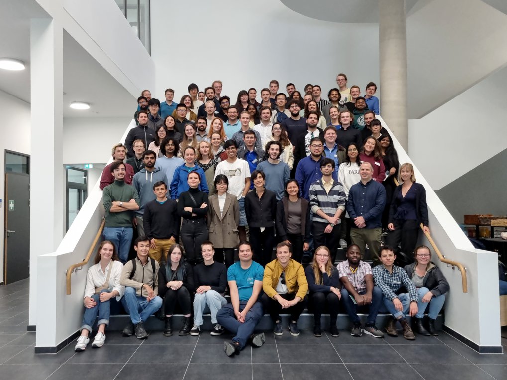 A large group of individuals positioned on a wide staircase inside a contemporary building.