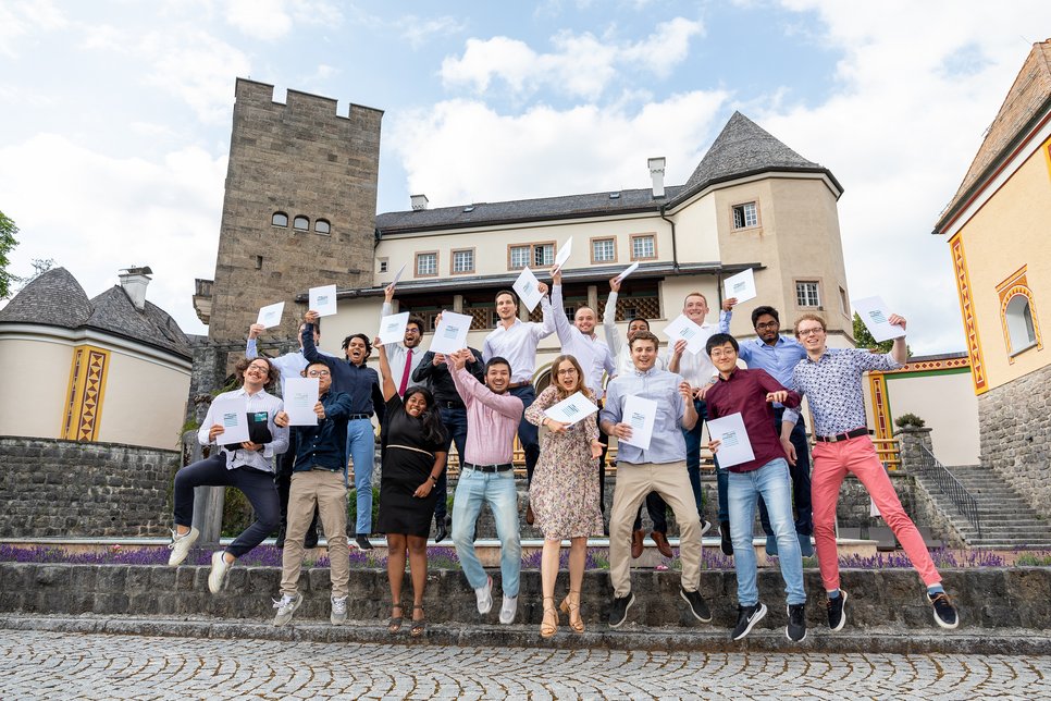 Another picture from the inner courtyard, in the middle of the same scenery: Around 20 students hold their certificates in their hands and jump up, cheering.