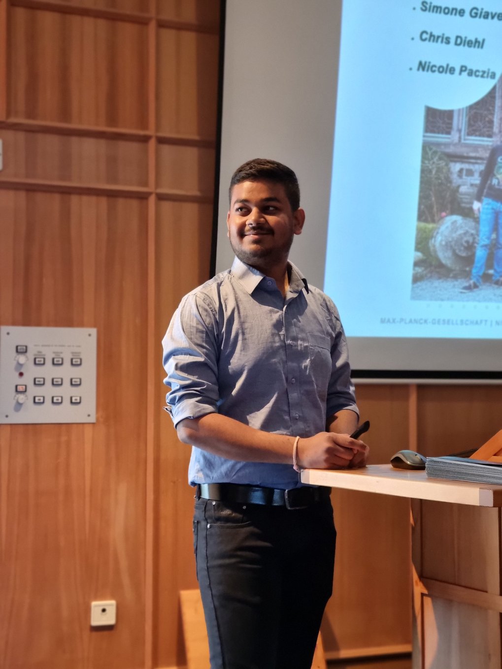 An MtL student stands at the lectern during the Q & A session after his lecture and looks to his left with a smile.