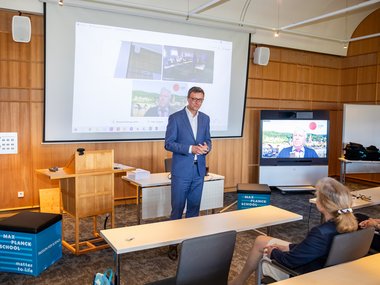 Patrick Cramer, President of the MPG, gives a short speech. The room is bathed in wooden colors.