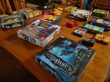 A selection of board games lies on a wooden table