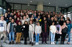 Matter to Life PhD candidates participating in the MtL Spring Days 2024 stand on the stairs at the main entrance of the physics building at the University of Göttingen