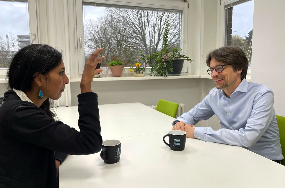 Matter to Life Fellow Thorsten Moos and Matter to Life coordinator Dharanija Madhavan sit at a table and have a conversation. 