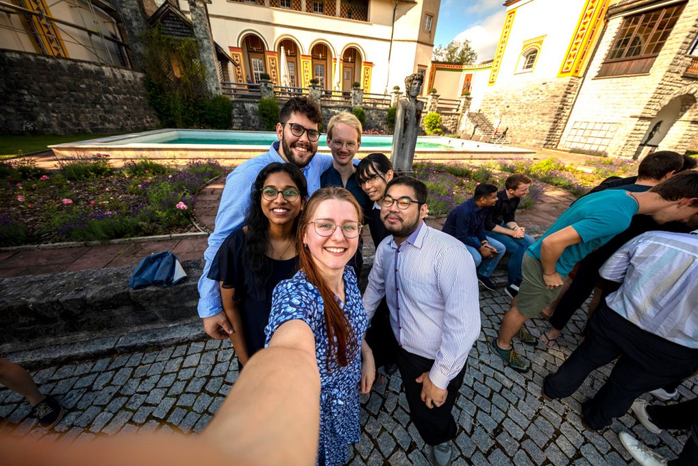 Three female and three male students take a selfie. The scenery of Ringberg Castle can be seen in the background