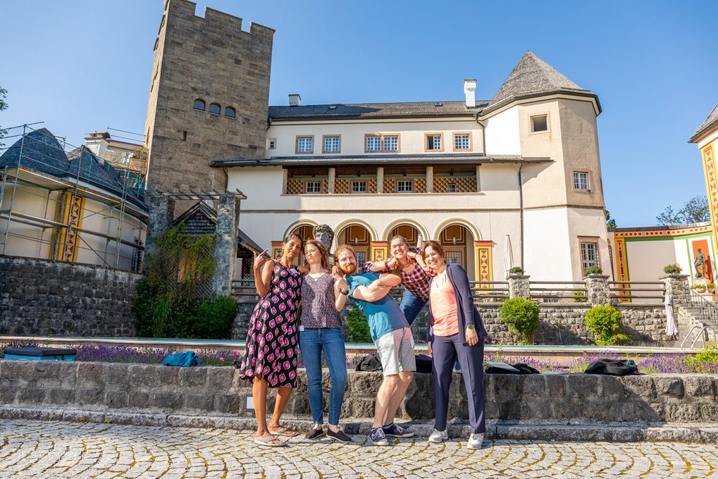 Four female coordinators and one male coordinator of the Max Planck School Matter to Life pose for the camera. Ringberg Castle can be seen in the background.