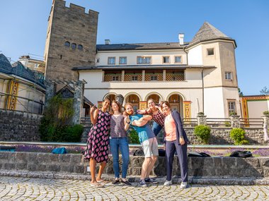 Four female coordinators and one male coordinator of the Max Planck School Matter to Life pose for the camera. Ringberg Castle can be seen in the background.