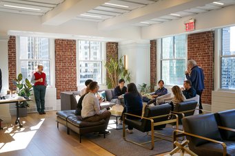 Democratic Discussions: Everyone gets a seat at the ‘table’ A group of Matter to Life conference participants converse in a bright lounge with brick walls, large windows, and modern furniture