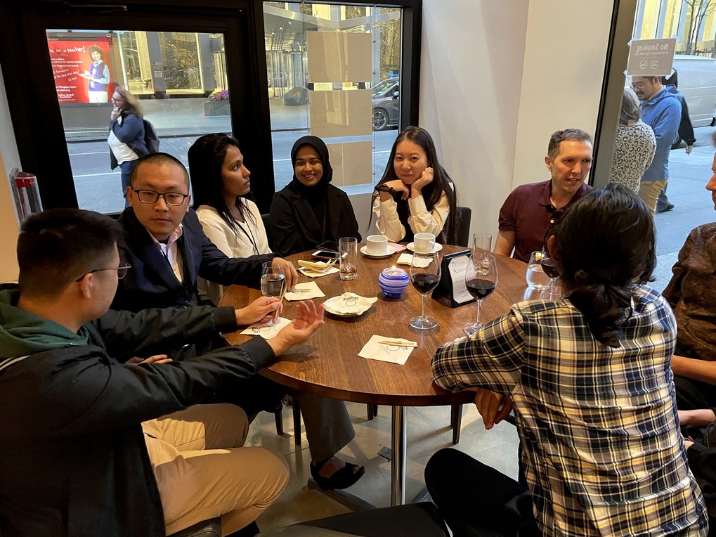 A group of participants at the Matter to Life conference are sitting at a table in a restaurant, chatting and drinking something.