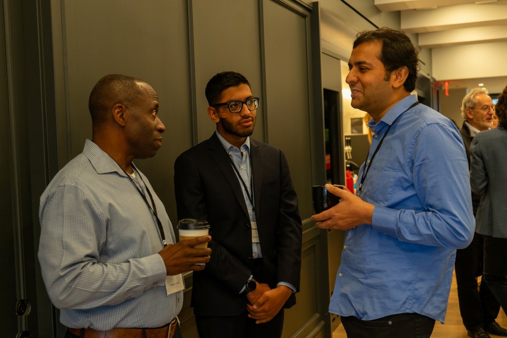 Three men engaged in conversation, one holding a coffee cup, creating a casual and collaborative atmosphere.