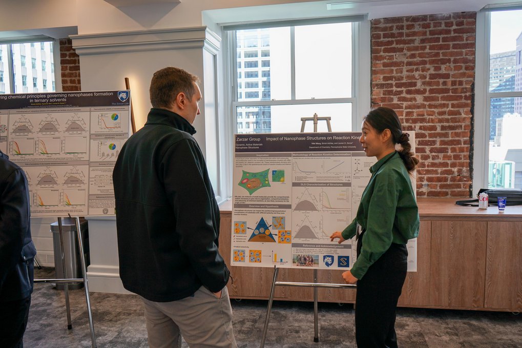 Two people have gathered around a scientific poster and are discussing.
