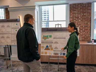 Two people have gathered around a scientific poster and are discussing.