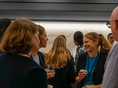 Lively discussion between a group of people. One of the women laughs.