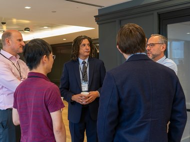 A group of Matter to Life conference participants gathered in a room, chatting and exchanging ideas.