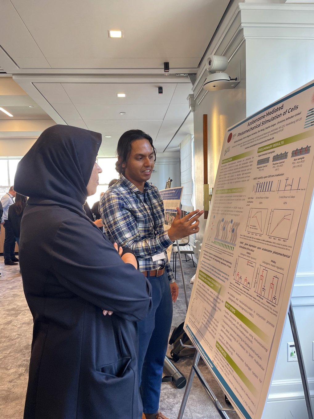 Two people stand in front of a poster display, discussing its content.