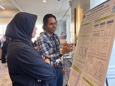 Two people stand in front of a poster display, discussing its content.