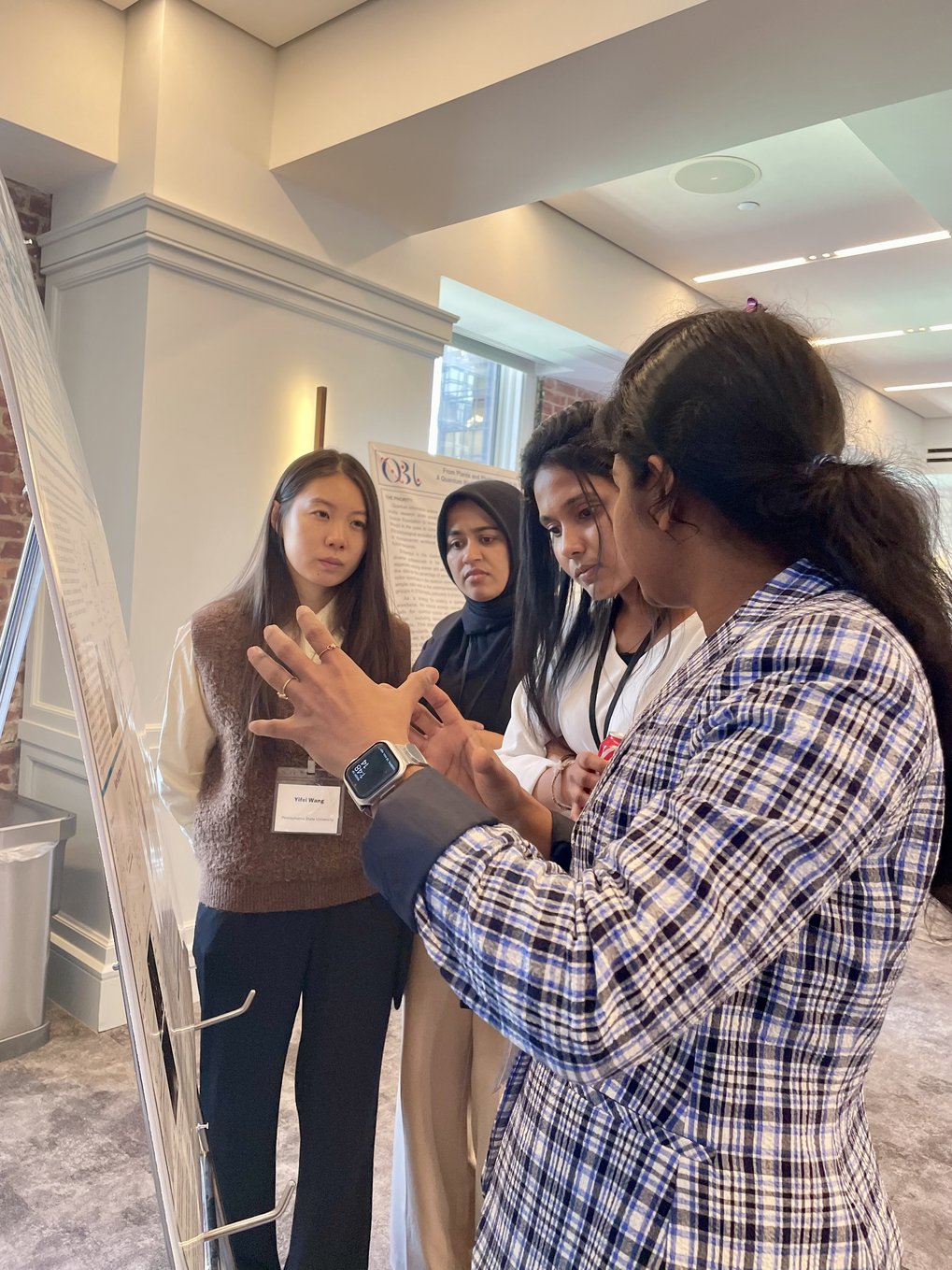 4 women standing in front of a scientific poster and discussing