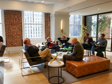Some people are sitting comfortably around a lounge table chatting.