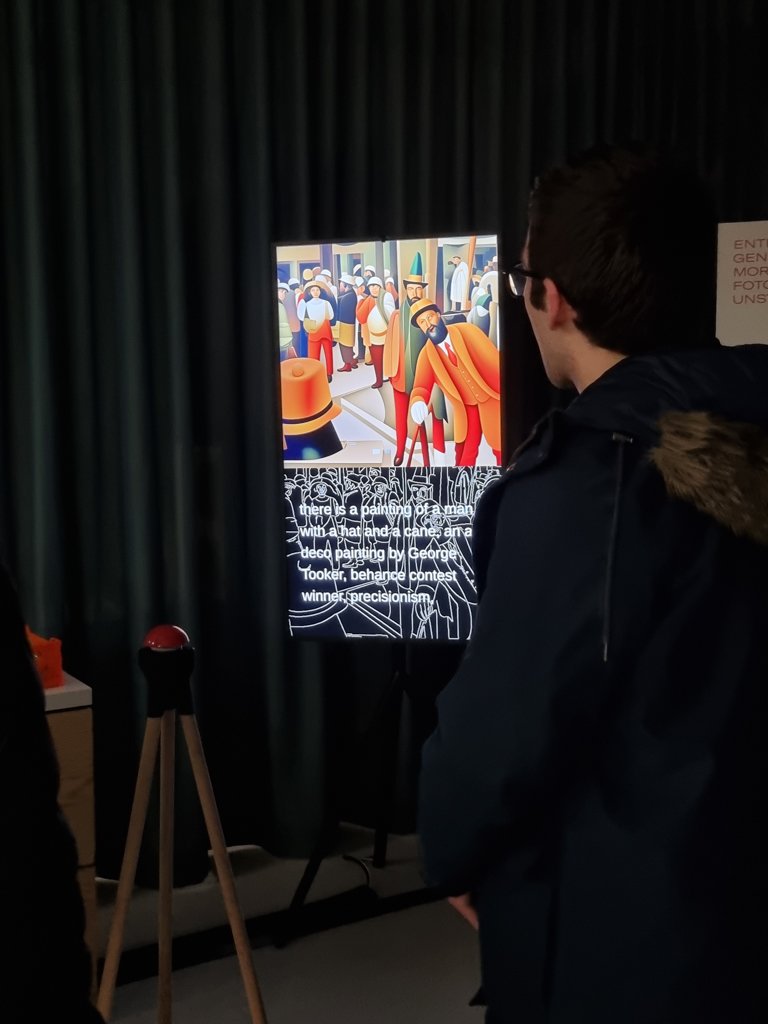 A person in a dark coat looks at a work of art on a large screen. The painting shows a group of people in vivid colors and geometric shapes. Curtains can be seen in the background.