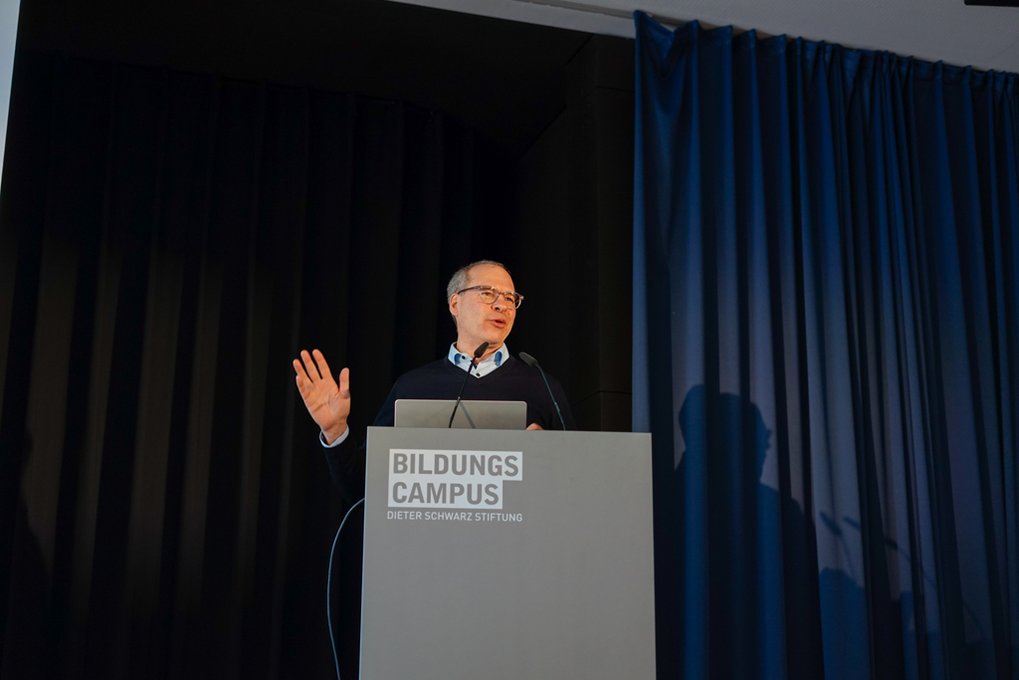 Ulrich Schwarz at podium with "Bildungscampus" logo, hand raised in gesture.