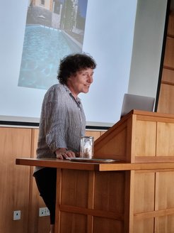 Petra Schwille is standing at a wooden podium and speaking.