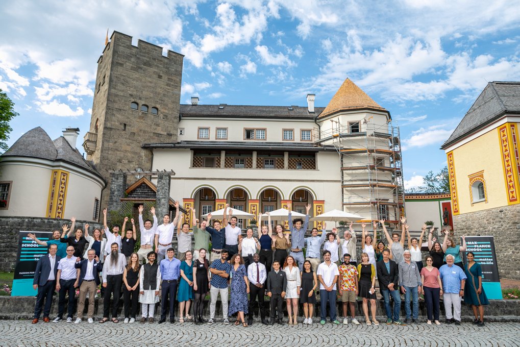 Group picture in front of the picturesque castle. Some participants are raising their hands.