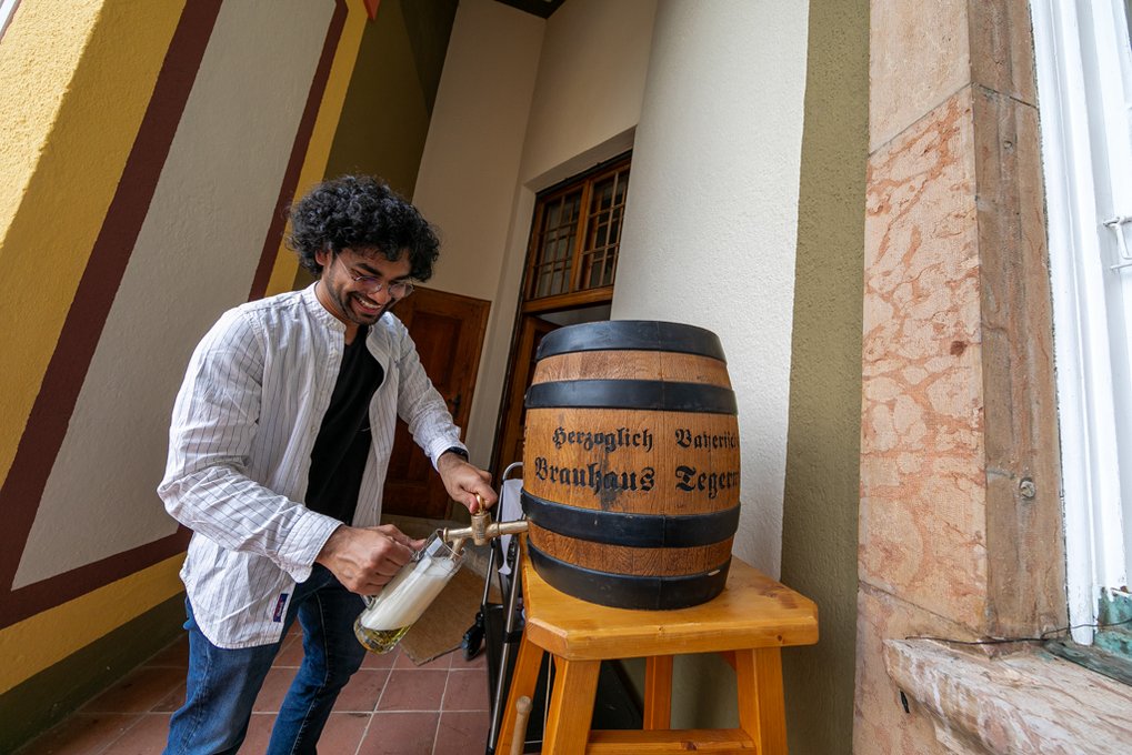 A student pours himself a beer from a large keg.