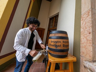 A student pours himself a beer from a large keg.