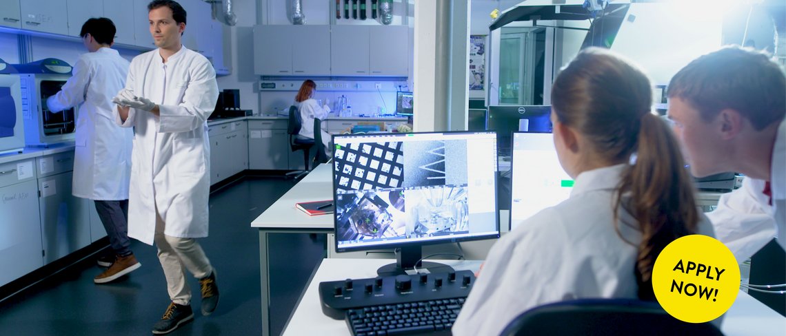 Matter to Life Students collaborating in a modern research lab using advanced scientific equipment for experimental work. In the lower right corner, there is a yellow button that says “Apply now.”