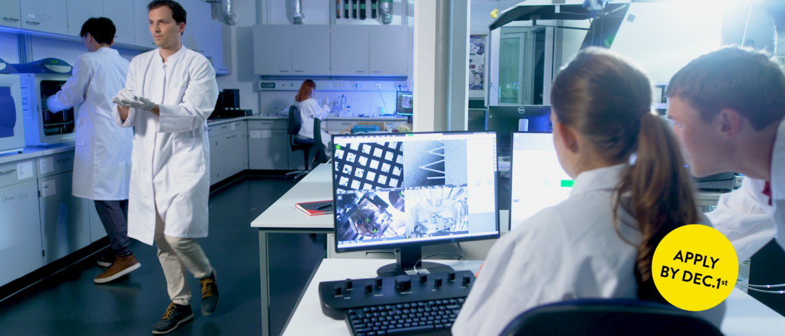Matter to Life Studierende in einem modernen Forschungslabor arbeiten gemeinsam mit hochentwickelter Technologie an wissenschaftlichen Projekten. Im Eck rechts unten befindet sich ein gelber Button in dem „Apply by Dec 1st.“ steht