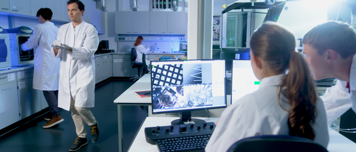 Matter to Life Studierende in einem modernen Forschungslabor arbeiten gemeinsam mit hochentwickelter Technologie an wissenschaftlichen Projekten.