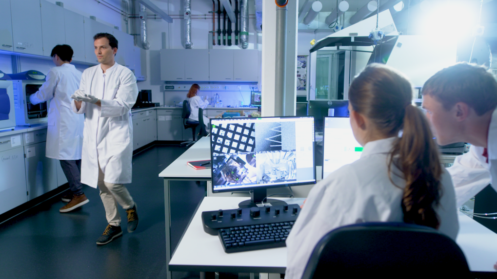 Matter to Life Studierende in einem modernen Forschungslabor arbeiten gemeinsam mit hochentwickelter Technologie an wissenschaftlichen Projekten.