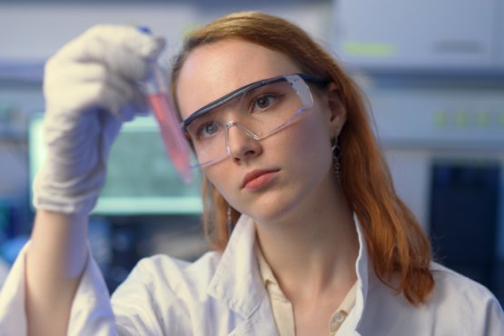 Matter to Life student wearing safety goggles examining a liquid sample in the lab