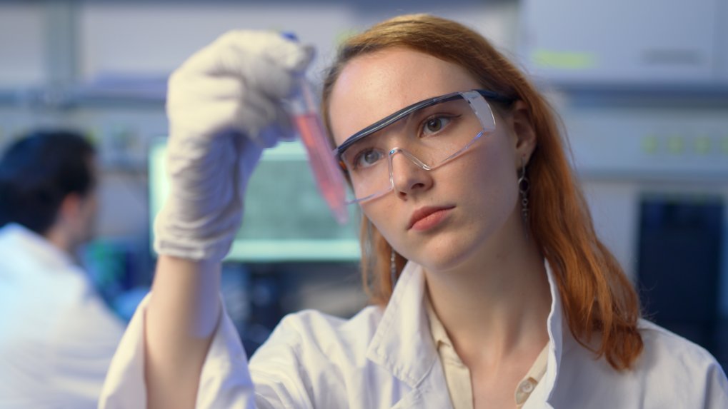 Matter to Life Studentin mit Schutzbrille untersucht im Labor eine Flüssigkeitsprobe