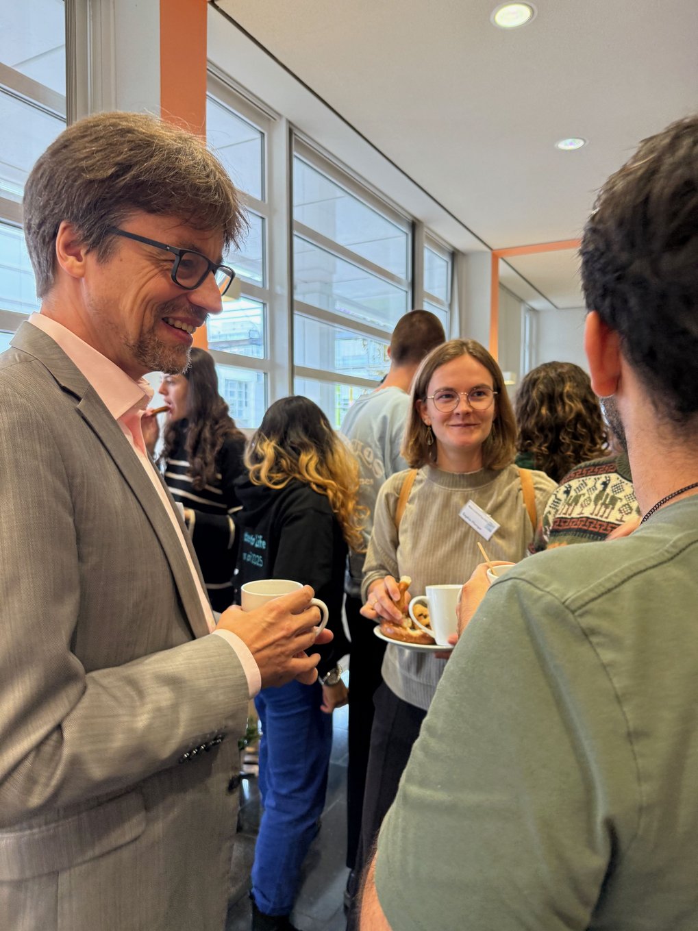 People at a networking event, holding cups and plates with snacks.