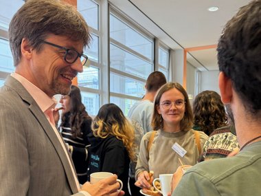 People at a networking event, holding cups and plates with snacks.