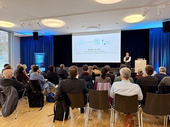 Joachim Spatz, Speaker of the Max Planck School Matter to Life kicked off the Fellow Meeting Attendees in a conference room listen to a speaker discussing molecular complexity, specificity, and non-equilibrium structures, titled "Matter to Life."