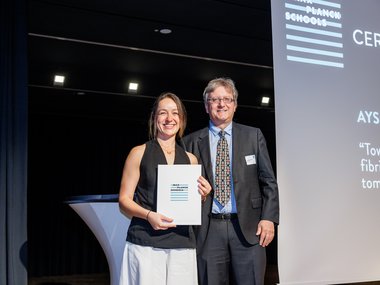 Aysecan Ünal smiling holding a Max Planck Schools certificate, standing beside Jan-Michael Rost in formal attire during an award ceremony.